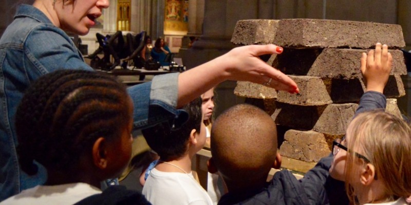 Woman pointing at bricks and educating young children