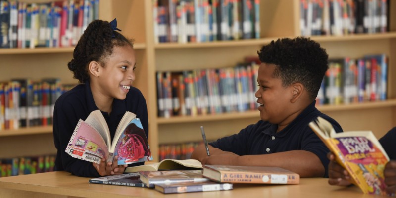 Two kids sitting in a library and reading