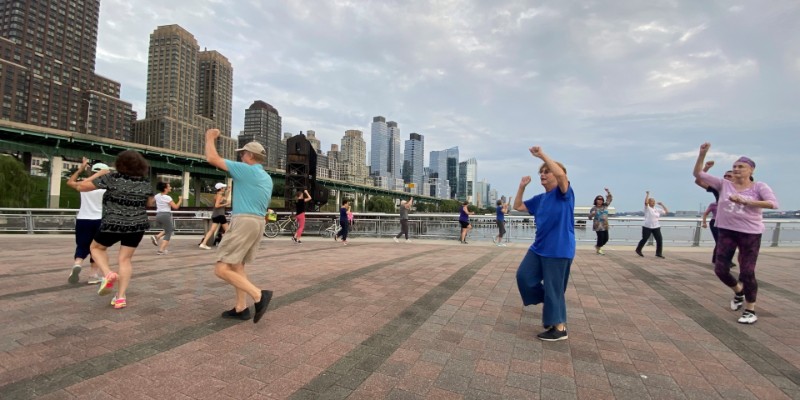 A group of older adults dancing on a pier.