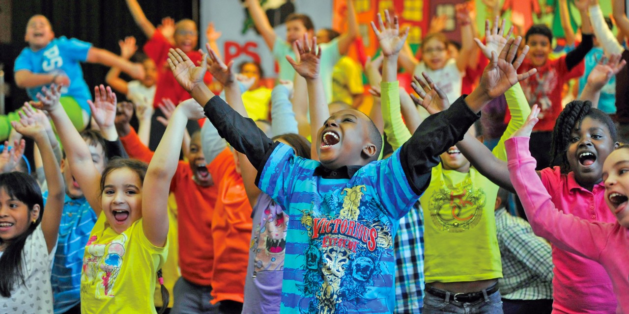 A group of children jumping and raising their arms in the air.