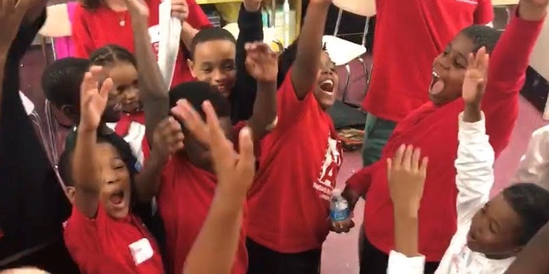 Group of kids raising their hands in excitment