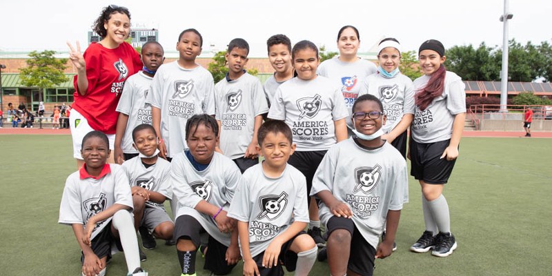 A group of children wearing America SCORES t-shirts