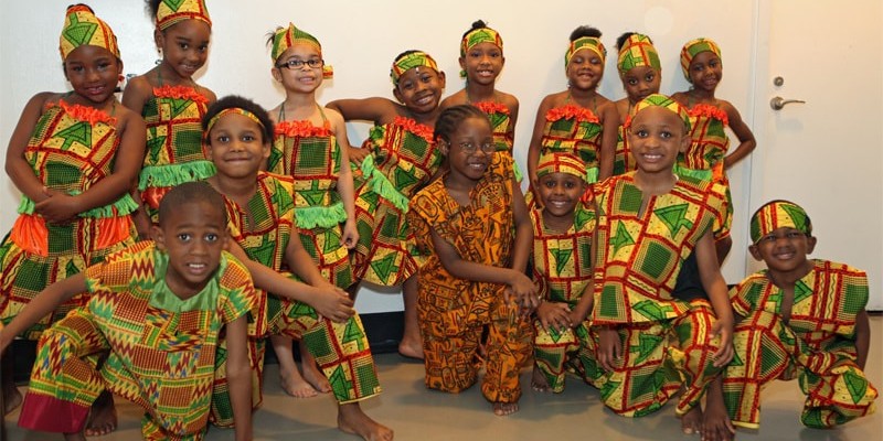 A group of children pose for the camera in outfits for a dance performance.