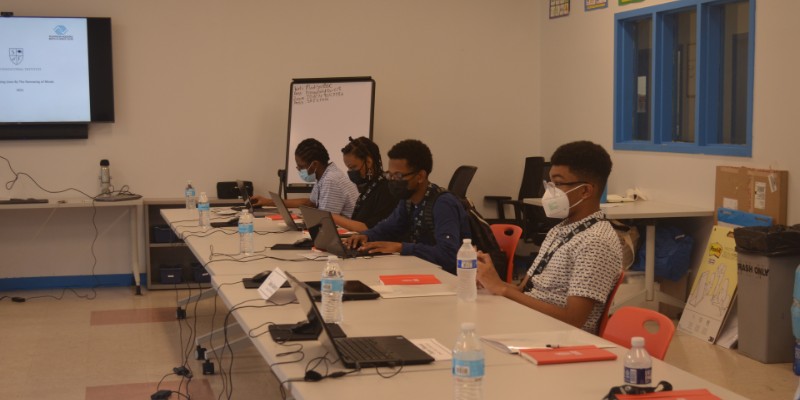 Four teenagers at a table using laptop computers.