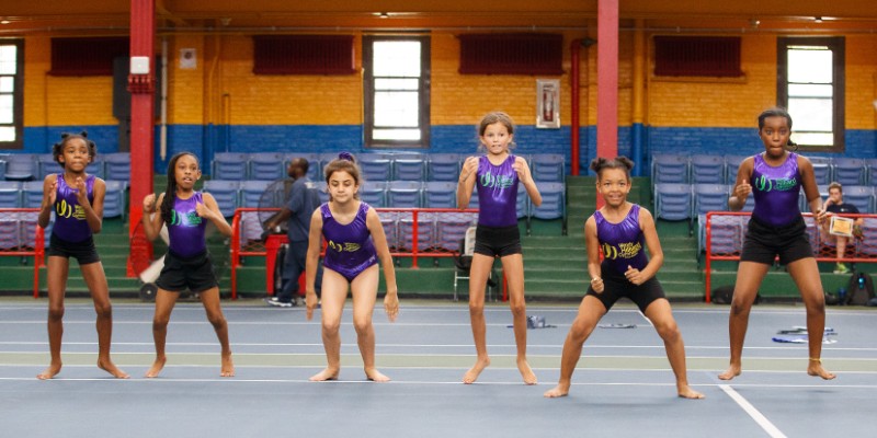A row of children in leotards jumping