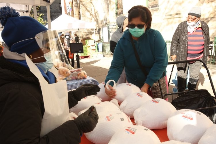 A woman in a mask takes a turkey from the table.