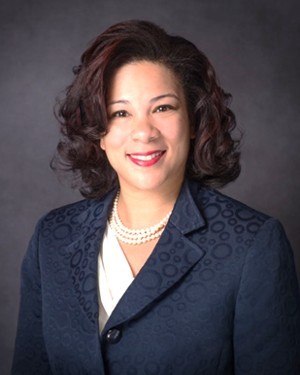 A headshot of a woman in a suit.