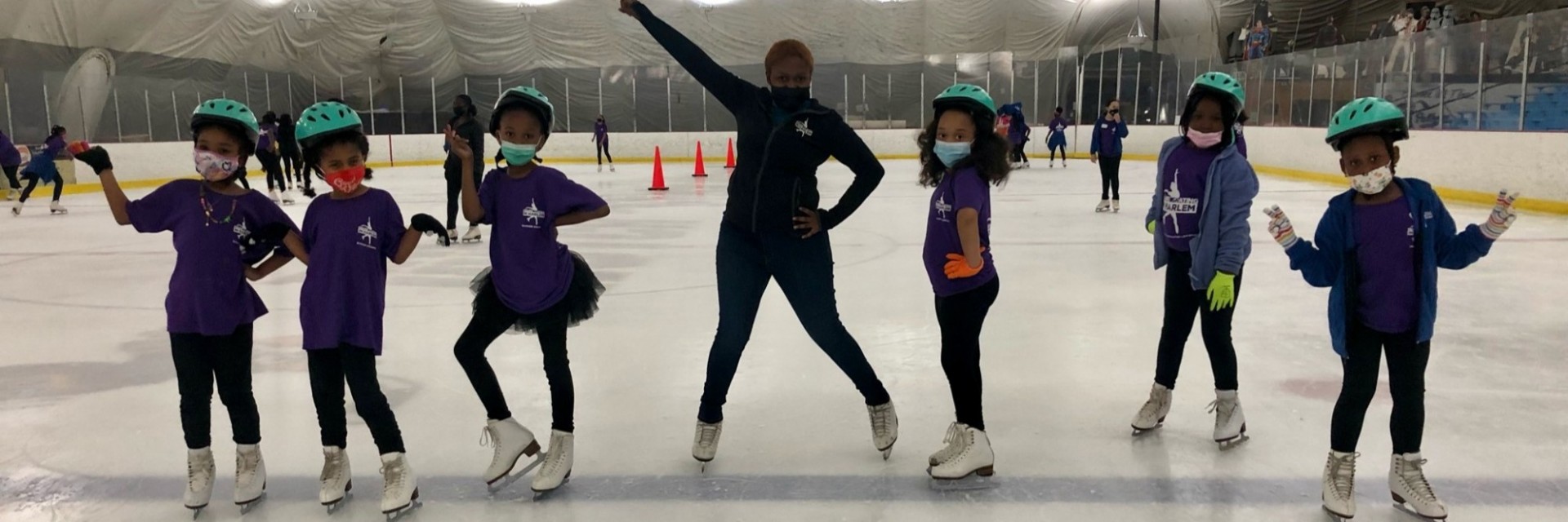 A group of girls ice skating with a teacher