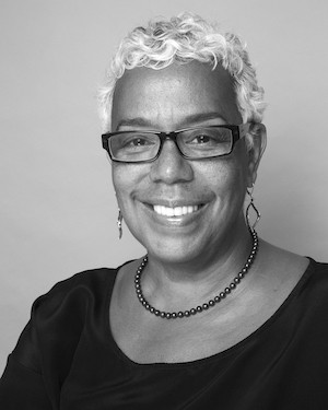 A woman with short white hair and glasses.