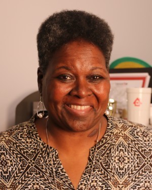 A headshot of a woman with natural hair smiling at the camera.