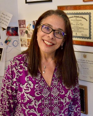 A headshot of a woman wearing glasses and a purple shirt.