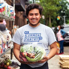 A man in an NYCP shirt holding a bag of food.