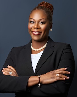 A woman wearing a black suit and white shirt smiling at the camera in a posed professional photo