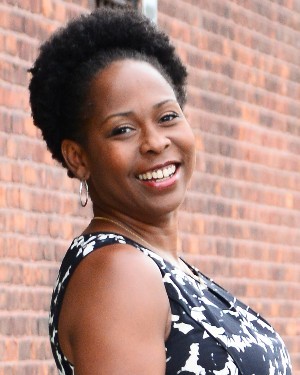 A headshot of a woman with natural hair.