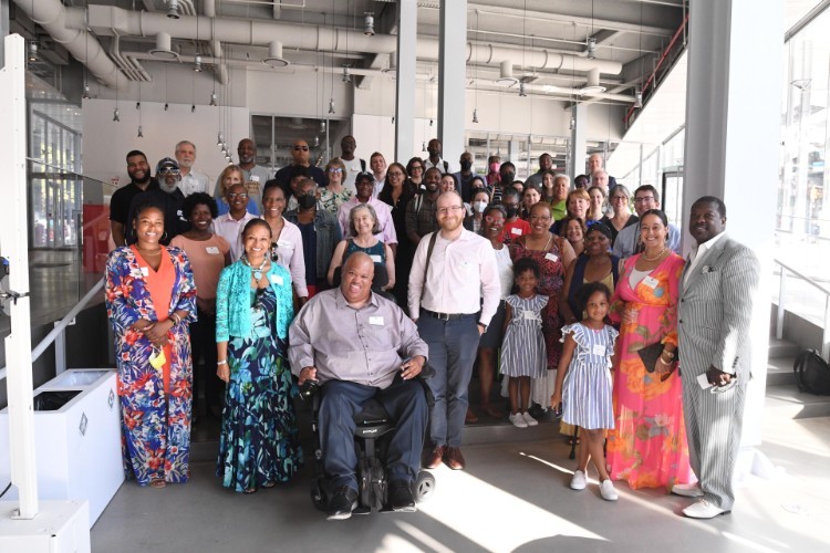 A large group of adults, with two children near the front, smiling at the camera