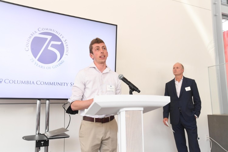 A man in a button-up shirt speaks into a microphone