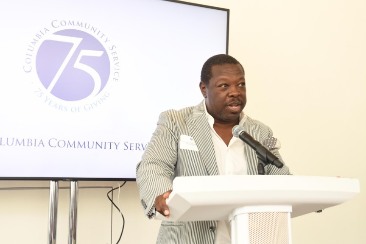 A man in a suit speaks into a microphone