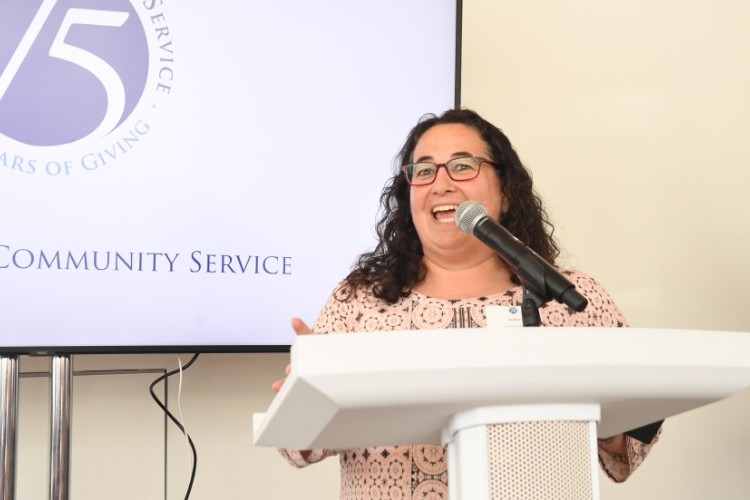 Photo by Eileen Barroso. A woman in a pink patterned shirt speaks into a microphone
