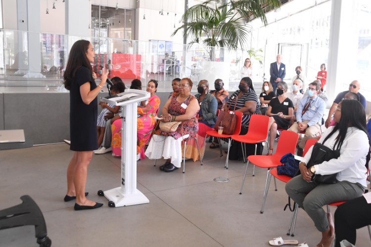 A woman in a black dress addresses a crowd