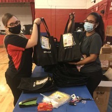 Two women holding black bags full of food.