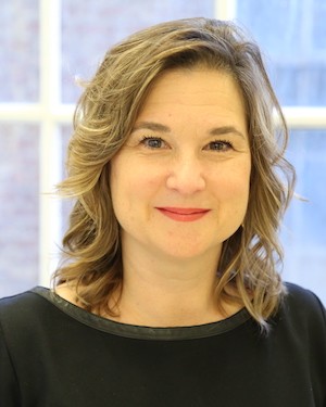 A woman in a black shirt smiles at the camera.