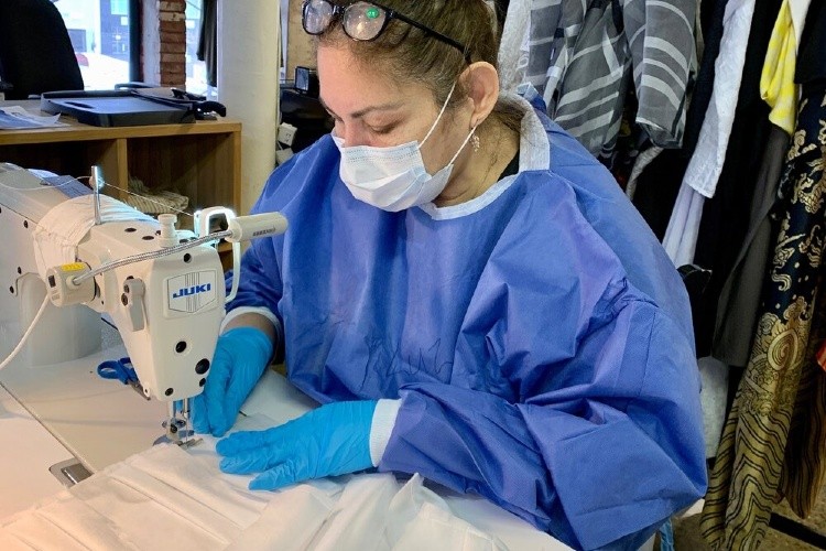 Woman in PPE sewing masks.