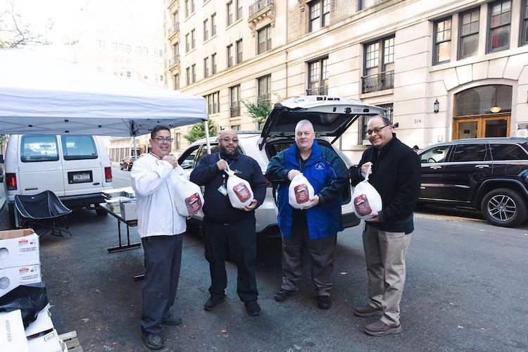 Four men holding bagged prepared raw turkeys.