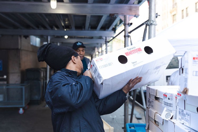 A man in a hat carries a box of turkeys.