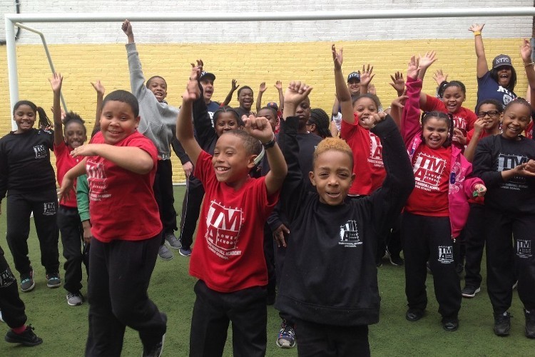 Participants in The Meeting House programming. A group of children in red and black t-shirts cheering.