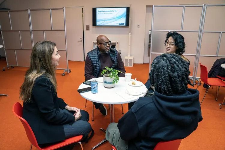 a group of people sitting at a table talking to each other 