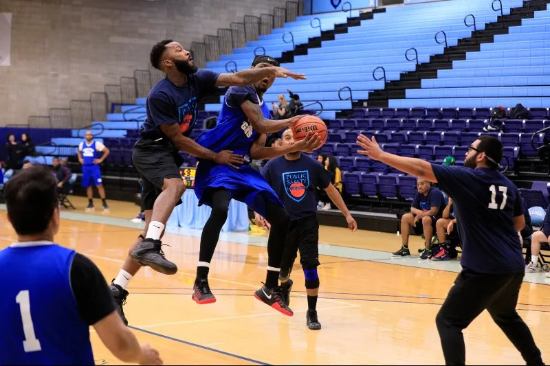 One man tries to steal a basketball from another man, while both of them are jumping in the air.